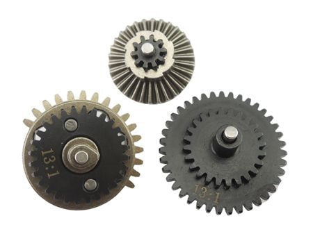 Three metal mechanical gears in different sizes and finishes, including one silver-toned gear and two black/gray gears with toothed edges, shown on a plain white background.