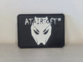 Black rectangular PVC airsoft patch with white stylized wolf mask and ATAIRSOFT logo by DISTRICT AIRSOFT