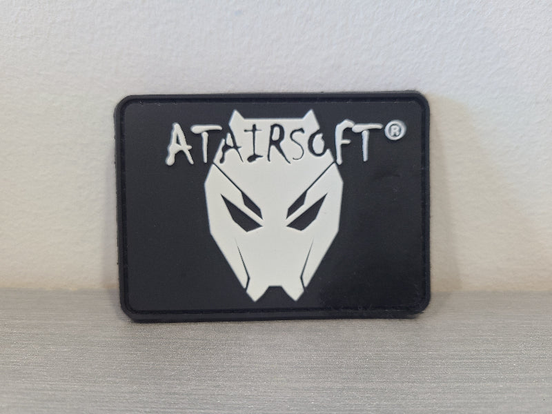 Black rectangular PVC airsoft patch with white stylized wolf mask and ATAIRSOFT logo by DISTRICT AIRSOFT