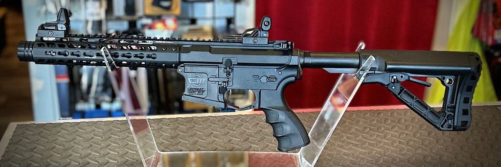 DISTRICT AIRSOFT AEG wild hog 9 black rifle with collapsible stock and MLOK style handguard on display stand