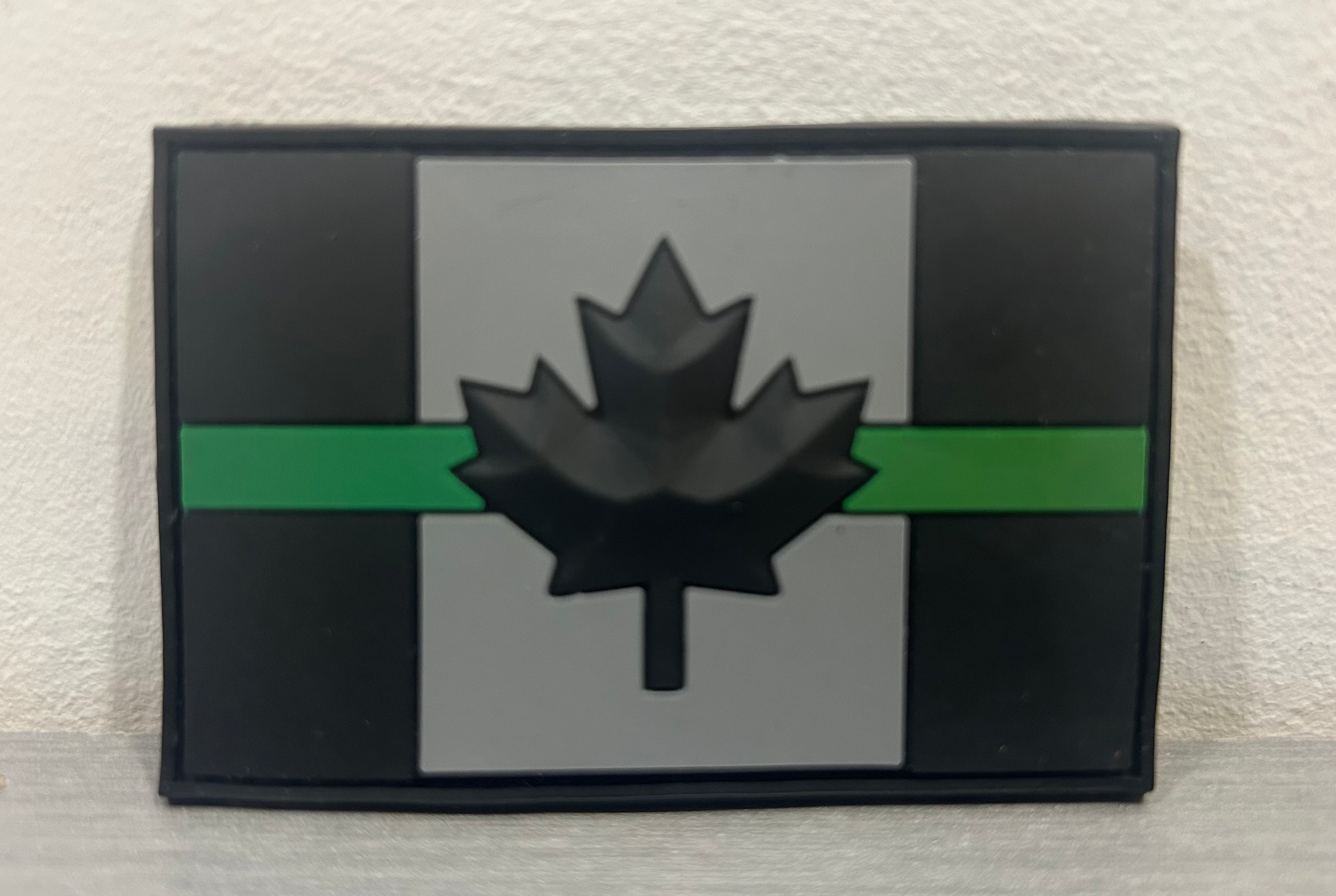 DISTRICT AIRSOFT Canada PVC Patch with Black Maple Leaf and Green Stripe on Gray Background