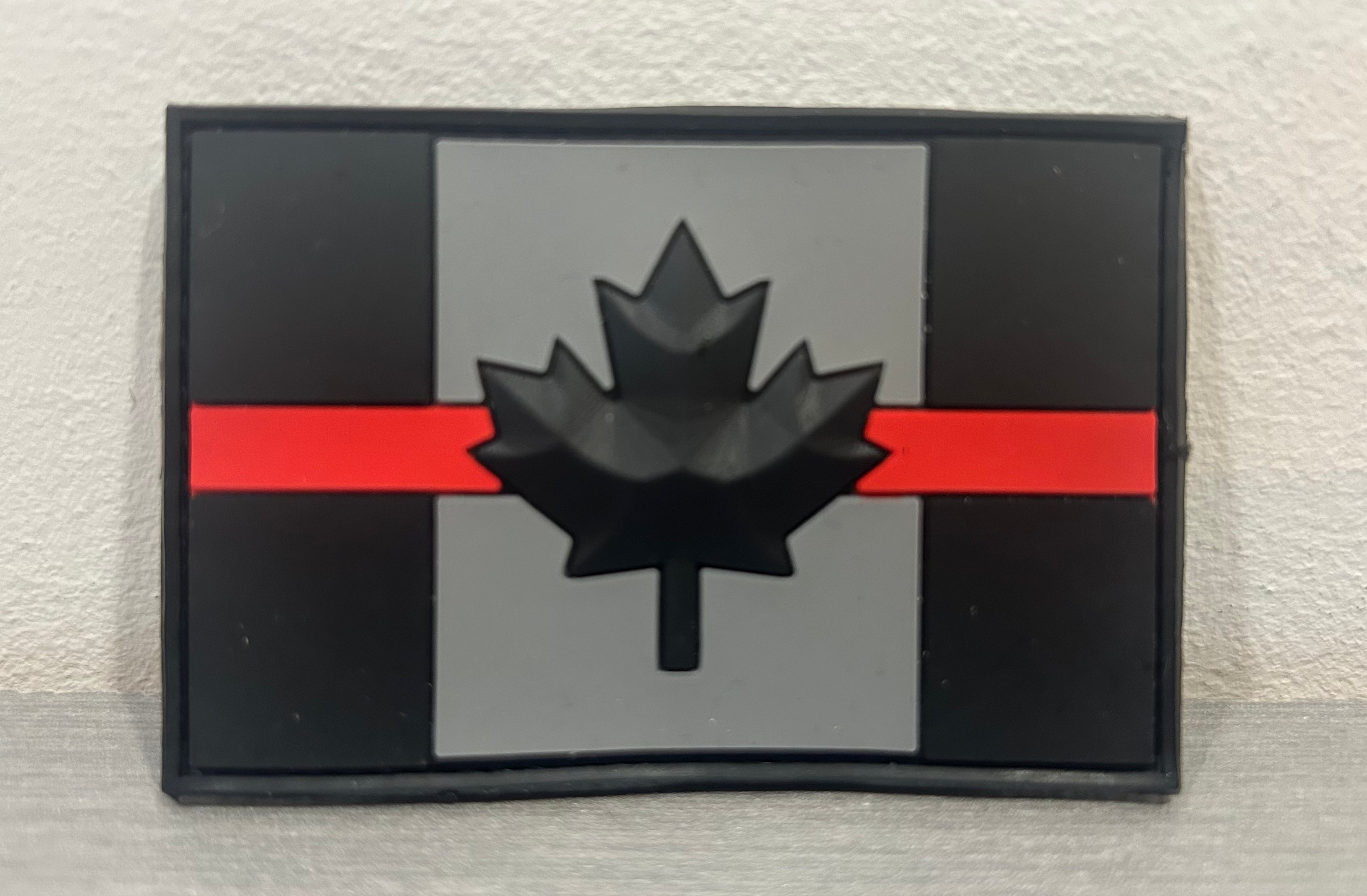 District Airsoft Canada PVC Patch with a black maple leaf on a grey background and red stripe