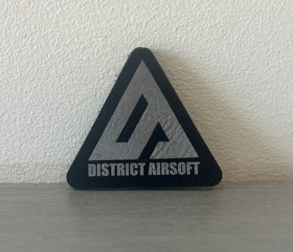 District Airsoft Leather Patch in a triangular shape with a bold logo for tactical enthusiasts