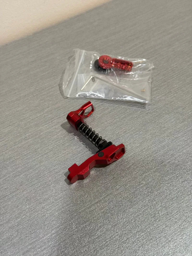 IPSC RED CHARGING BUTTON and accessories displayed with installation components for firearm enhancements