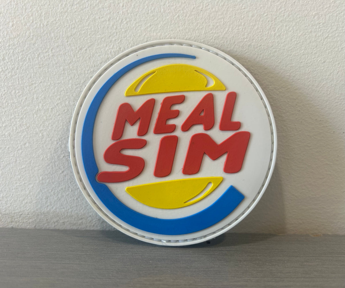 MEAL SIM PVC PATCH featuring a colorful design with bold lettering and playful graphics
