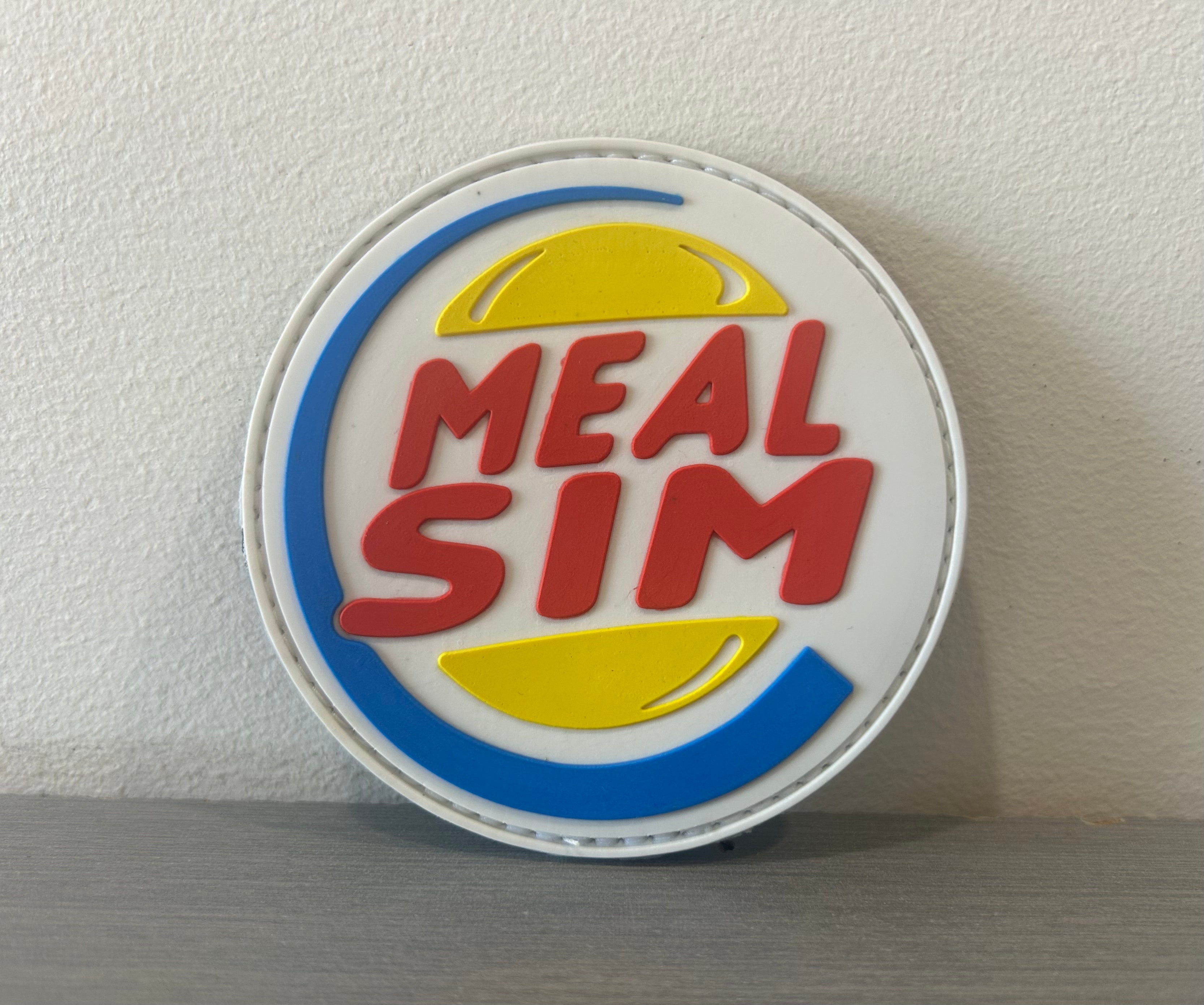 MEAL SIM PVC PATCH featuring a colorful design with bold lettering and playful graphics