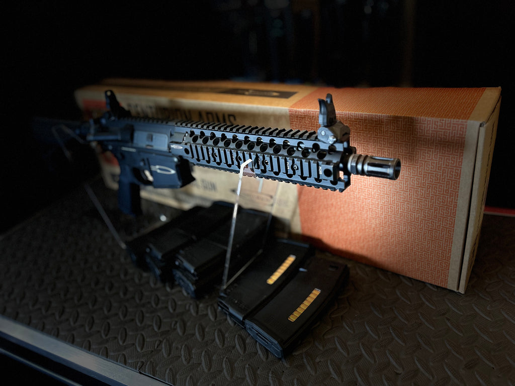 KWA AEG PTS Centurion with black handguard and three magazines on a display backdrop