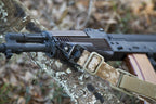 District Airsoft CEINTURE A DETACHEMENT camouflage quick detach rifle sling attached to AK style rifle on woodland log